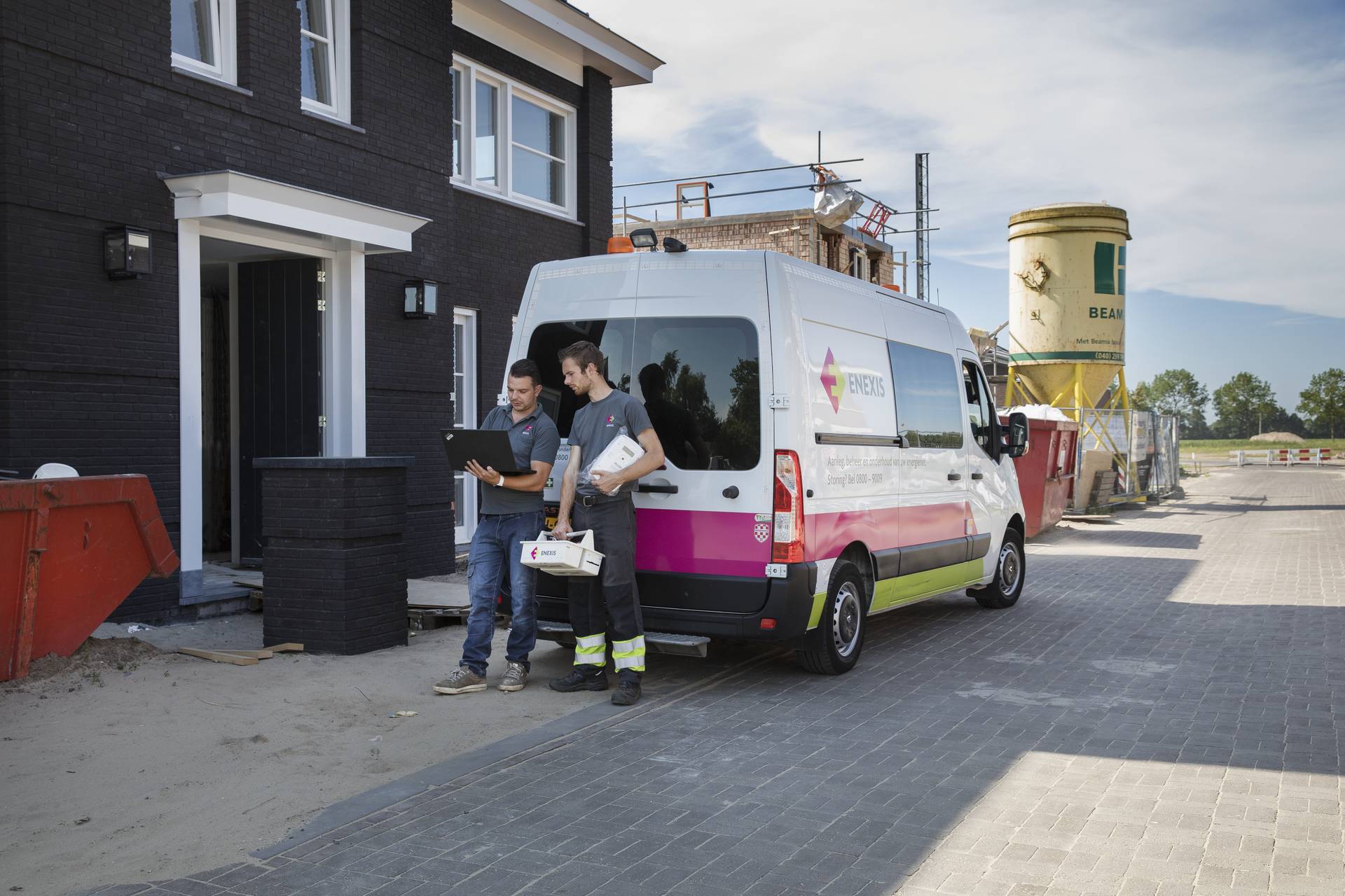 Monteur met werkbus bij nieuwbouwhuis voor nieuwe aansluiting Monteur met werkbus bij nieuwbouwhuis voor nieuwe aansluiting