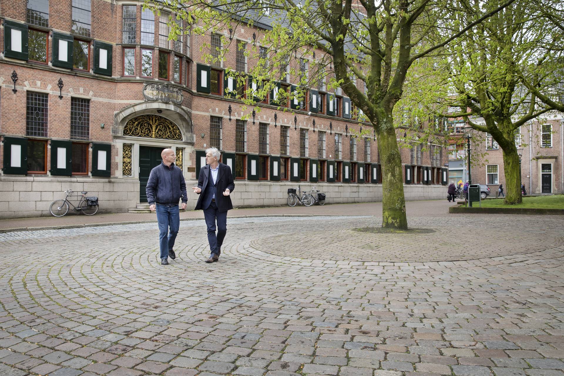 Twee mannen lopen voor een gemeentehuis Twee mannen lopen voor een gemeentehuis