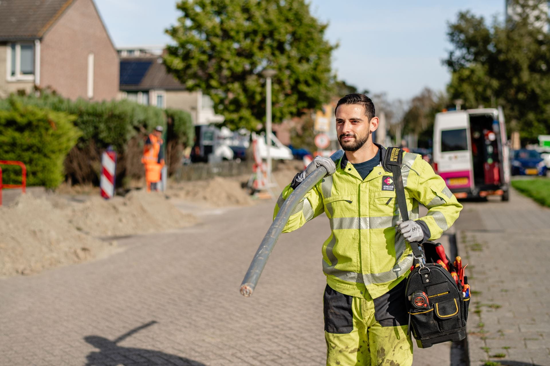 Een Enexis monteur draagt een kabel Een Enexis monteur draagt een kabel
